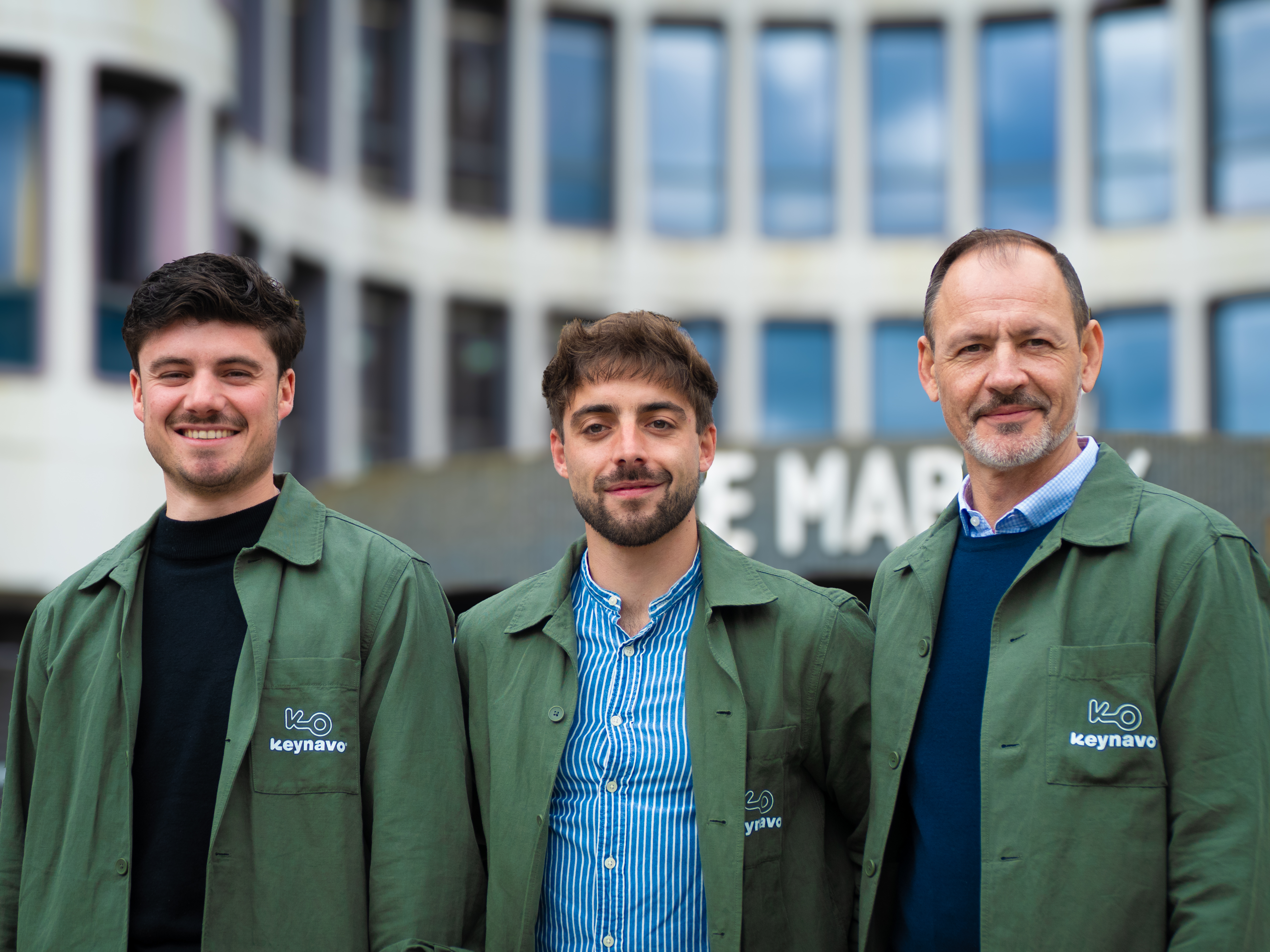 Les trois fondateurs de Keynavo, réunis devant Le Mabilay à Rennes. Ils portent une chemise à l’image de leur marque (couleur verte avec le logo Keynavo en beige). Ils ont le sourire et paraissent soudés.